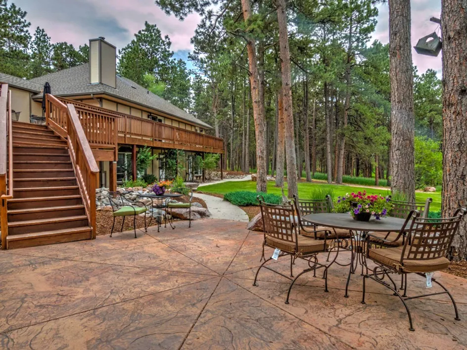 A wooden deck and patio area with furniture and trees in the background.