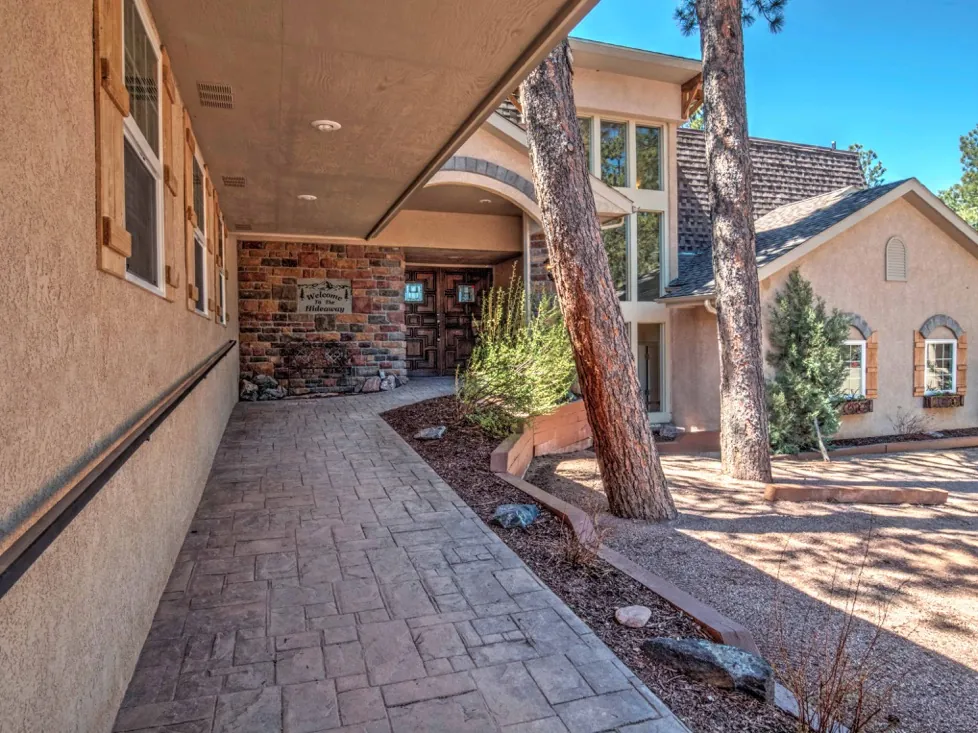 A beige stucco building with a brick accent wall and a paved walkway leading to the entrance.